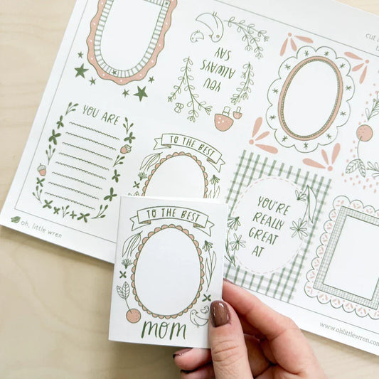 hand holds a folded mother's day zine with text 'to the very best mom' and blank space for drawing. background shows full free printable zine page.