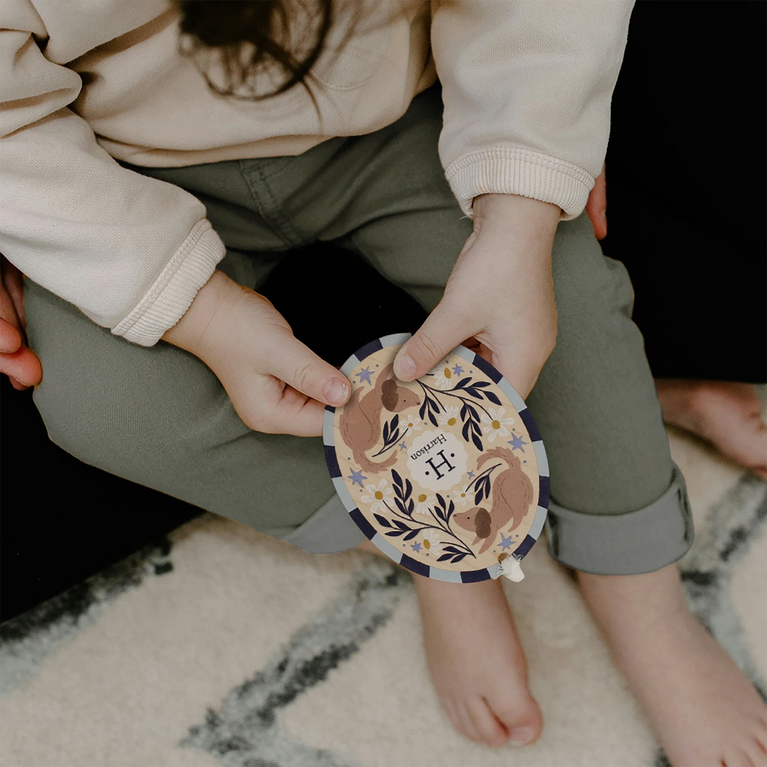 child holding custom name christmas ornament with the name harrison and a dog design