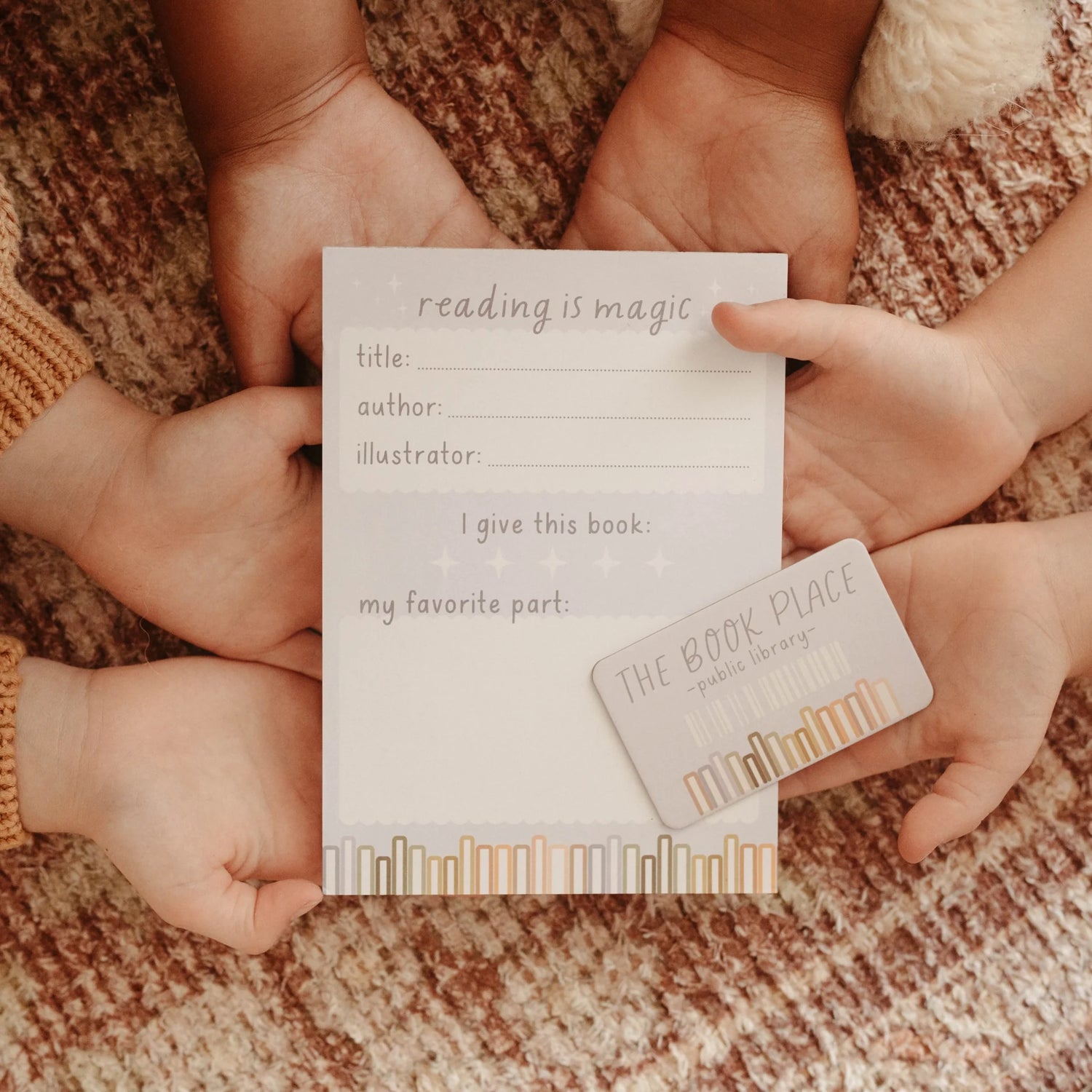 little kid hands holding a library notepad and pretend library card.