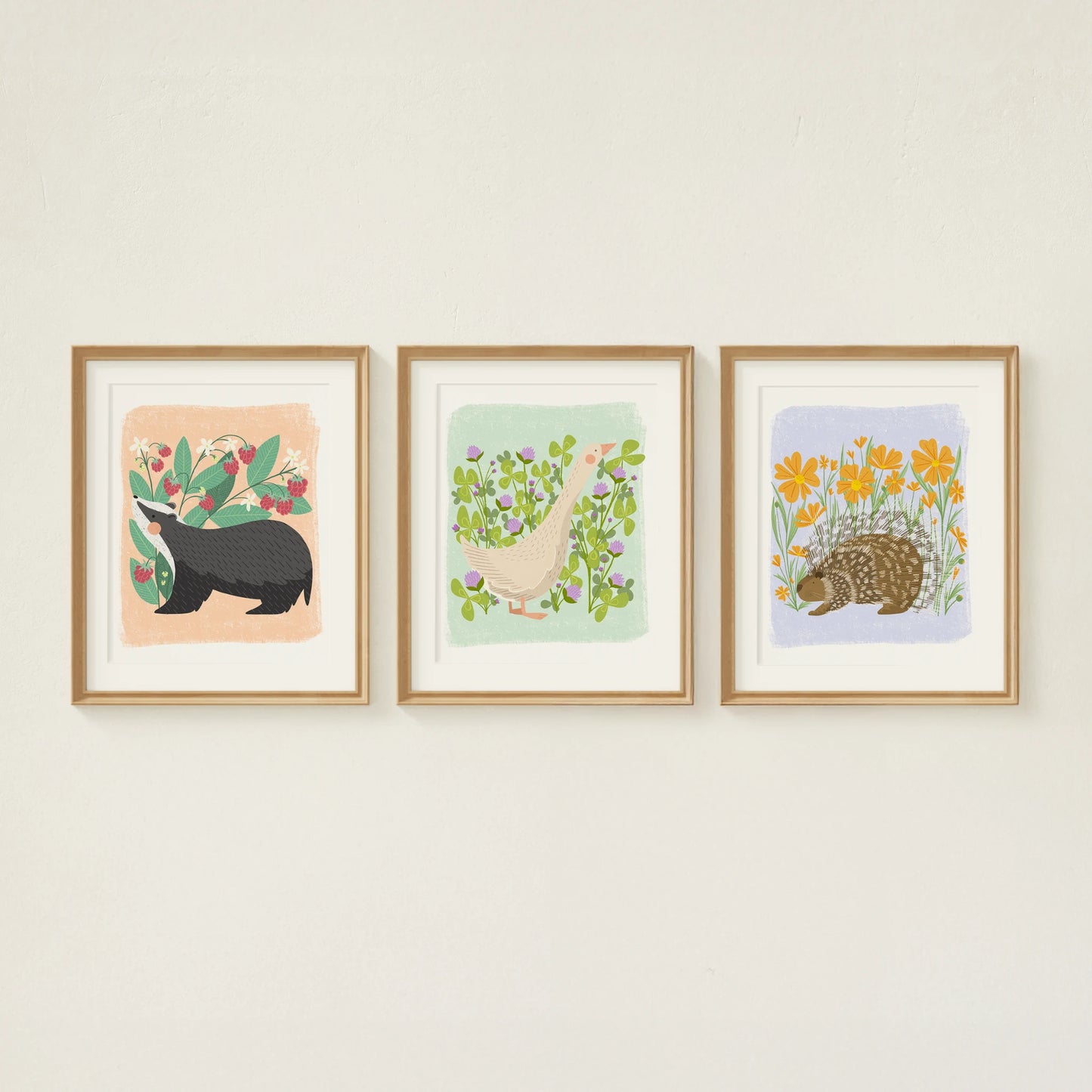 three cute animal art prints shown framed on the wall. from left to right: a badger, a goose, and a porcupine.