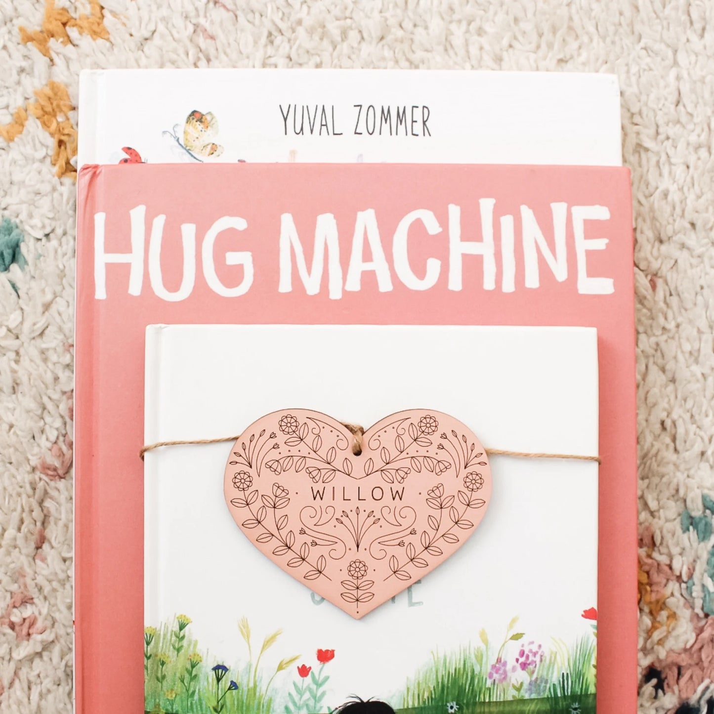 coral pink heart tag on top of a stack of books. tag has intricately etched floral designs and the name WILLOW.