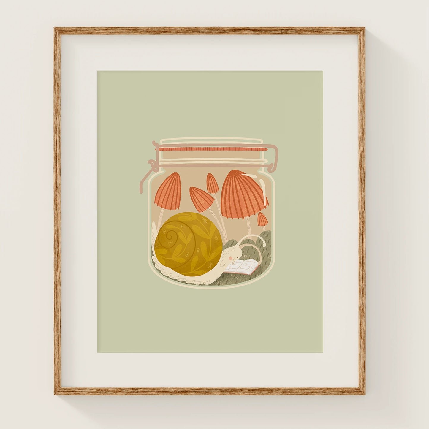 'slow afternoons' art print, shown in a wood frame. print features a snail among mushrooms, reading a book inside of a jar.