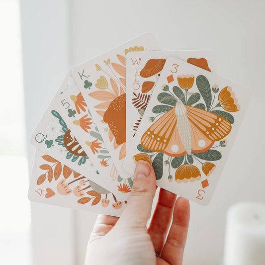 hand holding 5 playing cards with illustrations on them