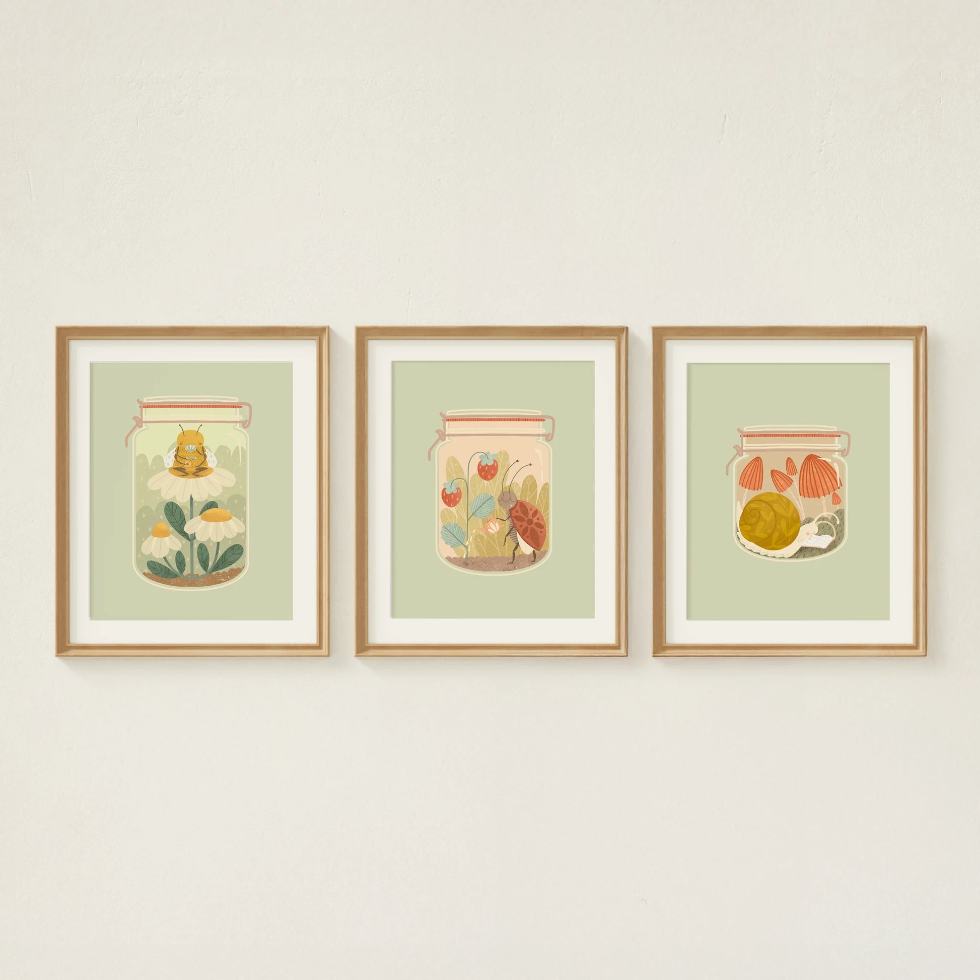 three art prints are shown hanging on the wall. from left to right: the bee's teas, tending to it, and slow afternoons. all feature insects in jars doing their cozy hobbies.