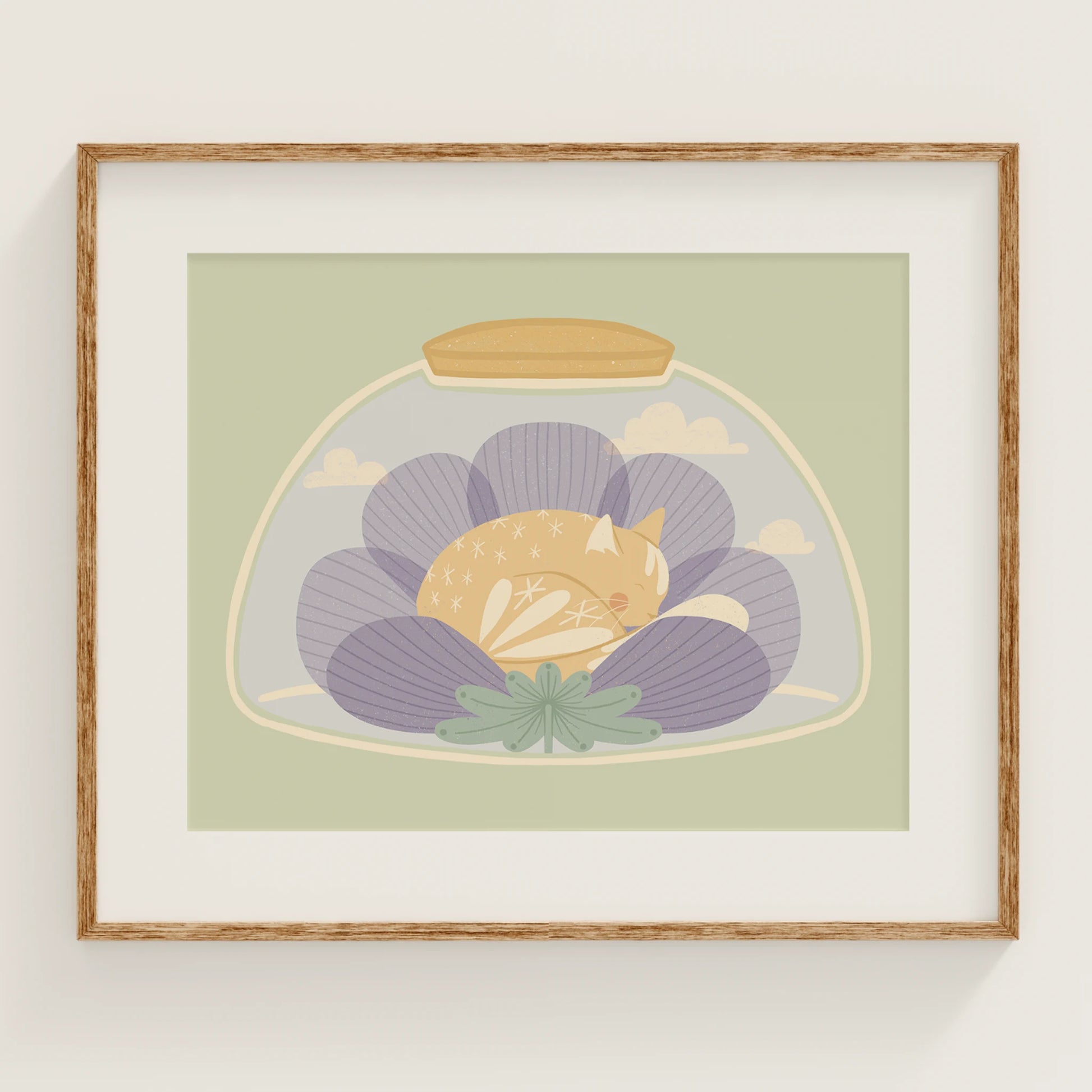 'a nap or two' art print, shown in a wood frame. print features cat sleeping inside of a flower, inside of a jar.
