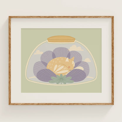 'a nap or two' art print, shown in a wood frame. print features cat sleeping inside of a flower, inside of a jar.