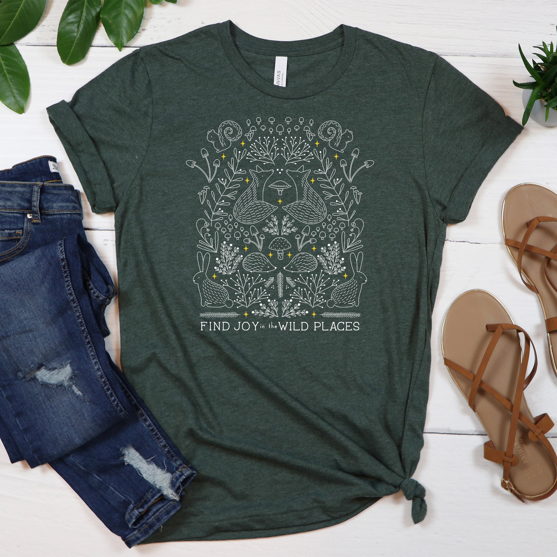 heather green t-shirt with the text 'find joy in the wild places' design features intricate foxes, hedgehogs, rabbit, plants and mushrooms.