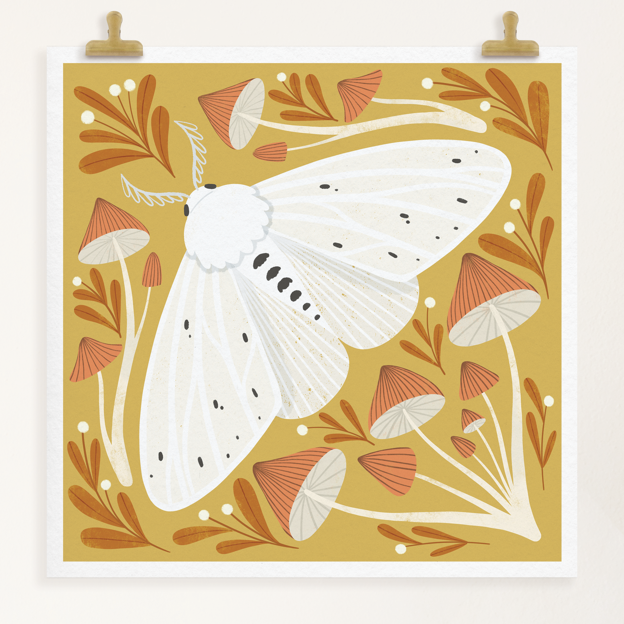 art print showing an agreeable tiger moth in black and white on a mustard yellow background, surrounded by red and white whimsical mushrooms. shown displayed hanging from two gold clips.