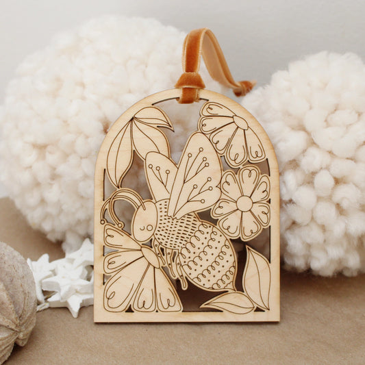 wooden bee arch shaped ornament with etched flowers and leaves.