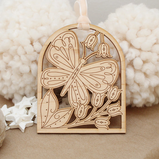 wooden butterfly arch shaped ornament with etched flowers and leaves.