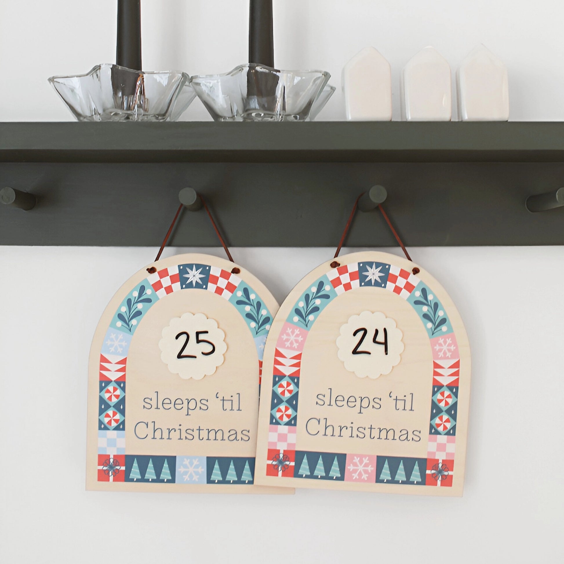two wood countdown sign with 'sleeps 'til Christmas' text and decorative patterns shown hanging on the wall