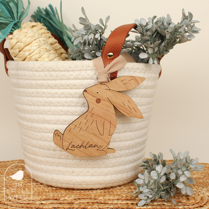 wooden easter bunny tag in cherry wood tone with the name Lachlan, shown hanging from a white rope basket.