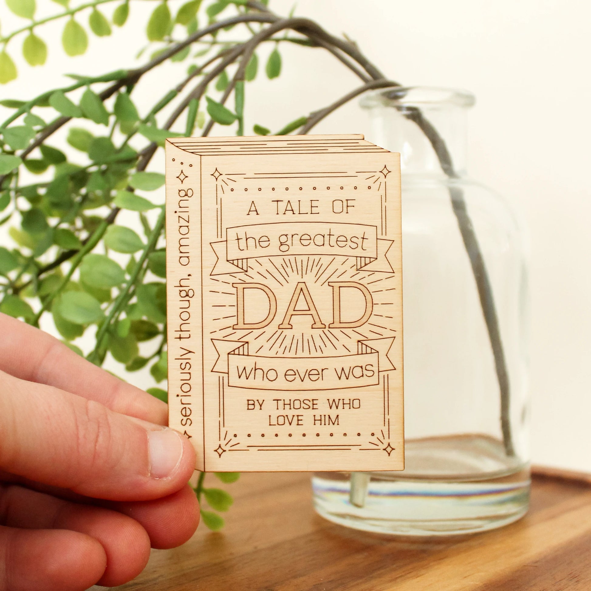 mini wood book shaped card. cover text reads 'a tale of the greatest dad who ever was by those who love him' and spine text reads 'seriously though, amazing'