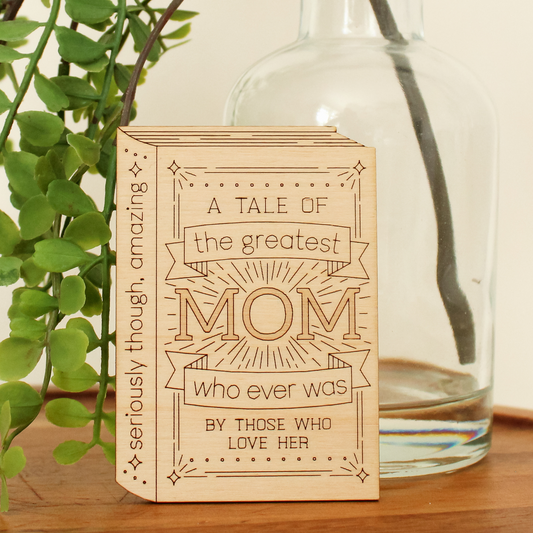 wooden book shaped card. cover reads 'a tale of the greatest mom who ever was by those who love her'. spine reads 'seriously though, amazing'.