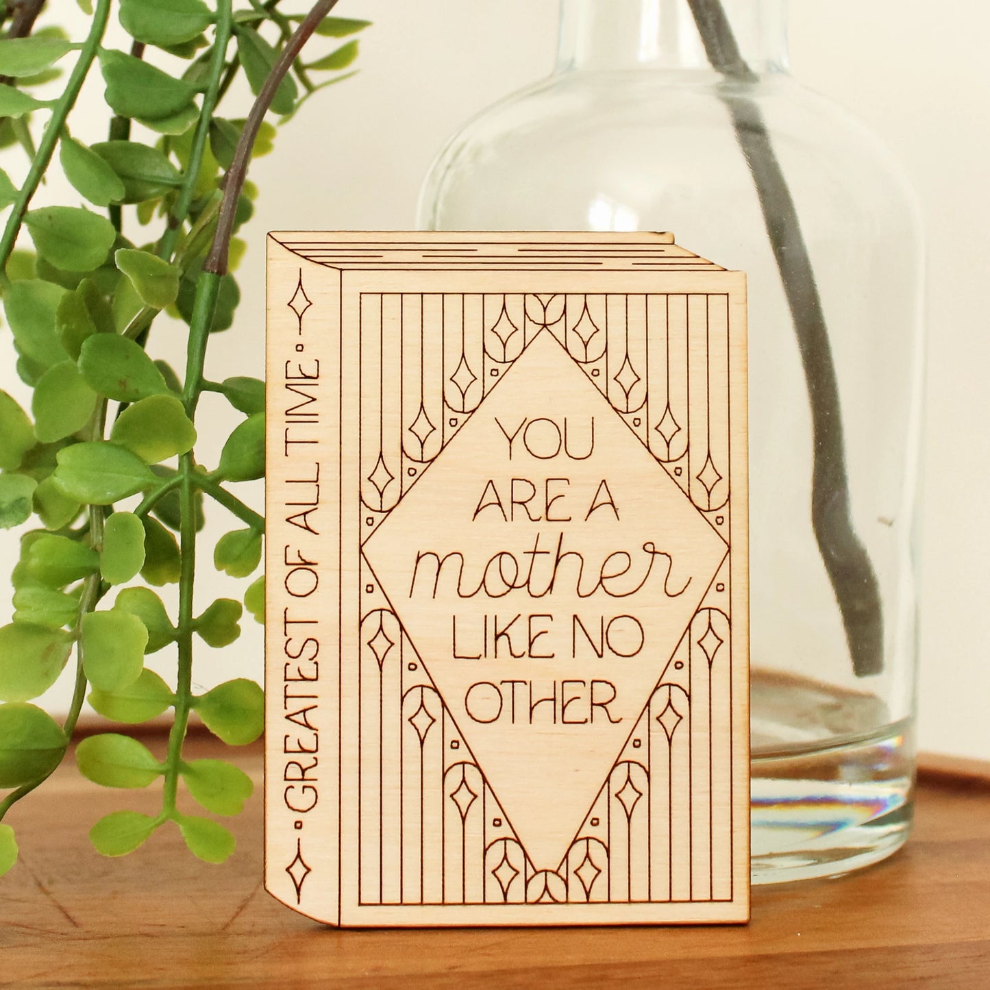 wooden book shaped card with floral motifs. cover reads 'you are a mother like no other'. spine reads 'greatest of all time'.