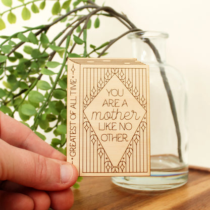 wooden book shaped card with floral motifs. cover reads 'you are a mother like no other'. spine reads 'greatest of all time'.