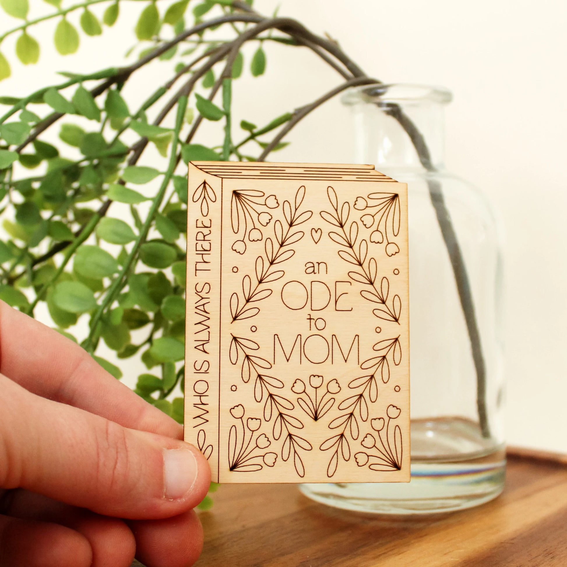 wooden book shaped card with floral motifs. cover reads 'an ode to mom'. spine reads 'who is always there'.