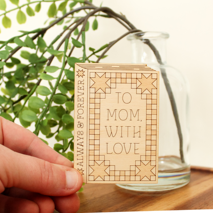 hand holding wooden book shaped card with quilt motifs. cover reads 'to mom with love'. spine reads 'always & forever'.