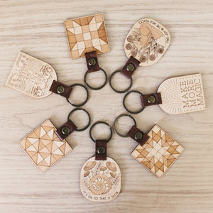 assorted wooden keychains with leather straps and bronze hardware.
