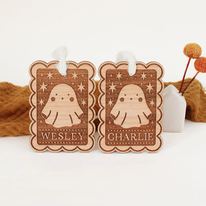 two personalized halloween tags with ghost designs propped up in front of an orange blanket. tags are customized with names WESLEY and CHARLIE.