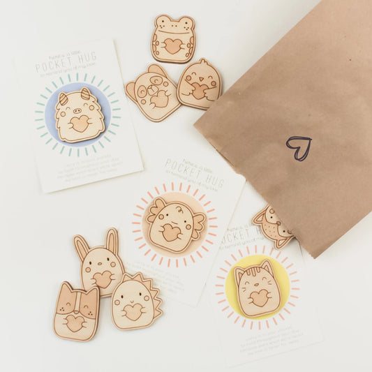 a collection of wooden pocket hugs, shown with a brown lunch sack, perfect for packing for back to school.