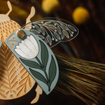 load image into gallery viewer, decorative wooden beetle, laser cut and layered with etched base, clear acrylic wings with a leaf design, and floral inlaid shell. wings and shell are movable as they&#39;re connected with a brass fastener. shell piece is dusty blue with a white flower with green leaves. shown close up of right half.
