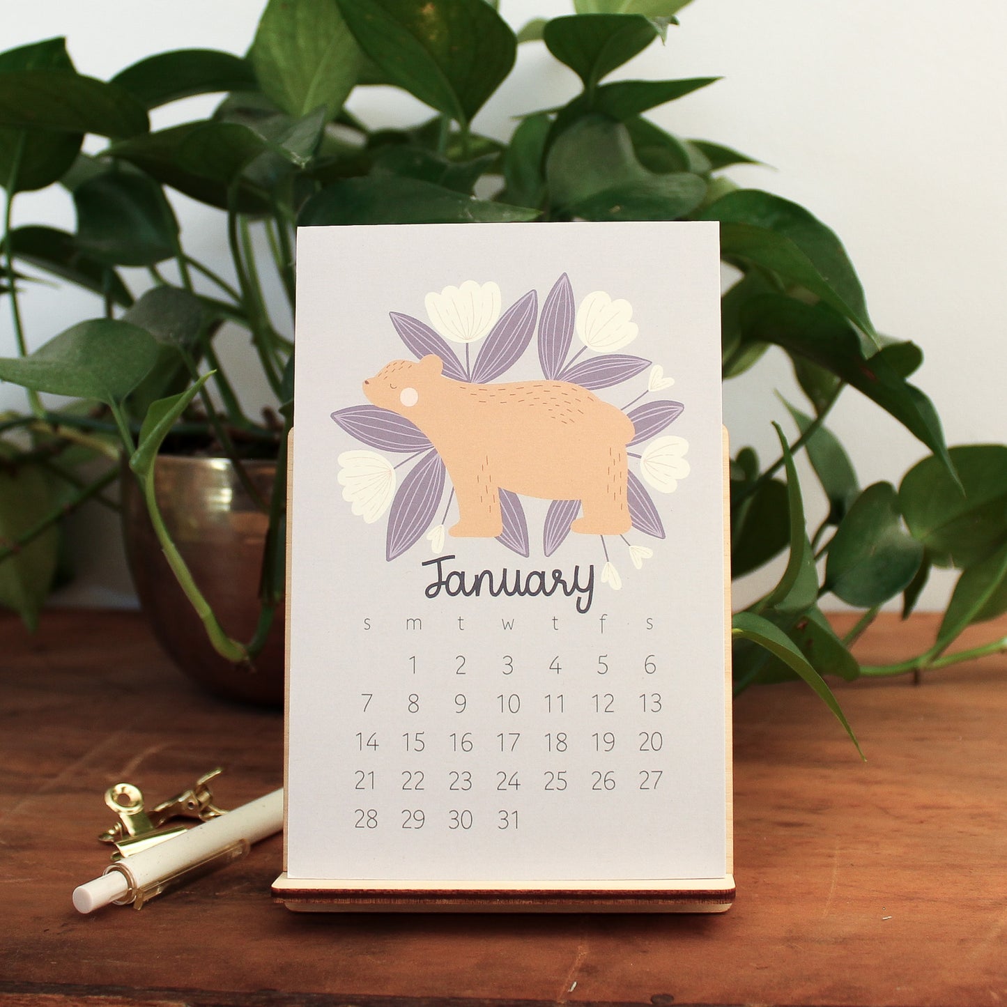 woodland animal 2024 desk calendar showing the month of january with a bear and white and purple flowers.