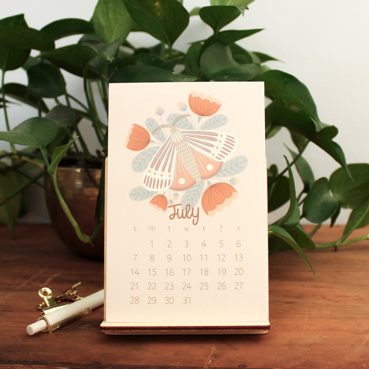woodland animal 2024 desk calendar showing the month of july with a moth and pink and red flowers.