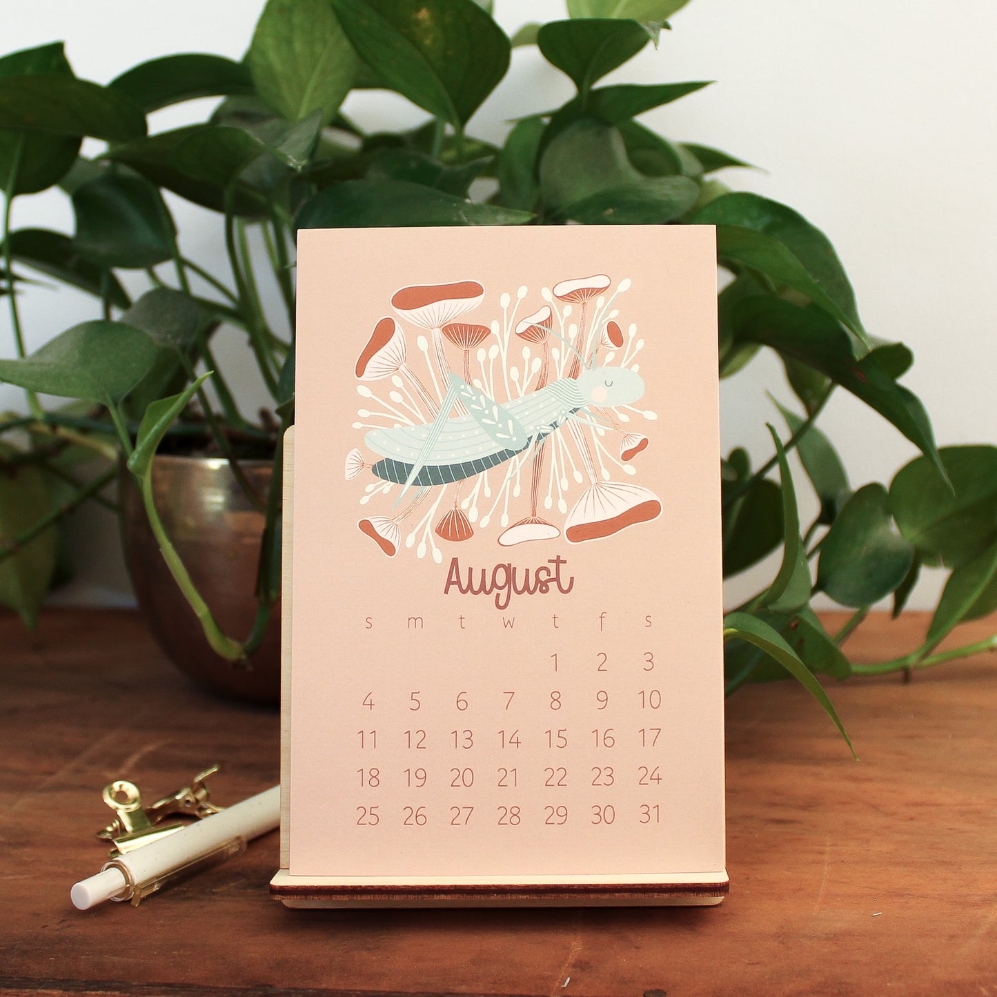 woodland animal 2024 desk calendar showing the month of august with a grasshopper and pink and rust mushrooms