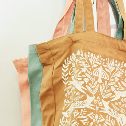 close up shot of 3 tote bags showing color comparision--from back to front coral pink, ocean blue, burnt orange.