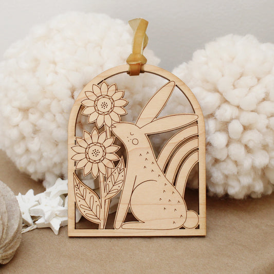 wooden rabbit arch shaped ornament with etched sunflowers and a rainbow