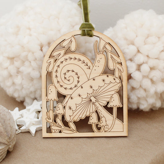 wooden snail arch shaped ornament with etched mushrooms and leaves.
