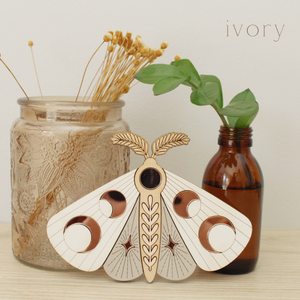 wooden moth with moon phase design. painted in ivory and taupe with wood tones and mirrored rose gold moon phase inlays.