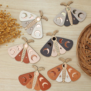 all 6 wooden moths with moon phase design. painted in an array of colors with wood tones and mirrored rose gold moon phase inlays.