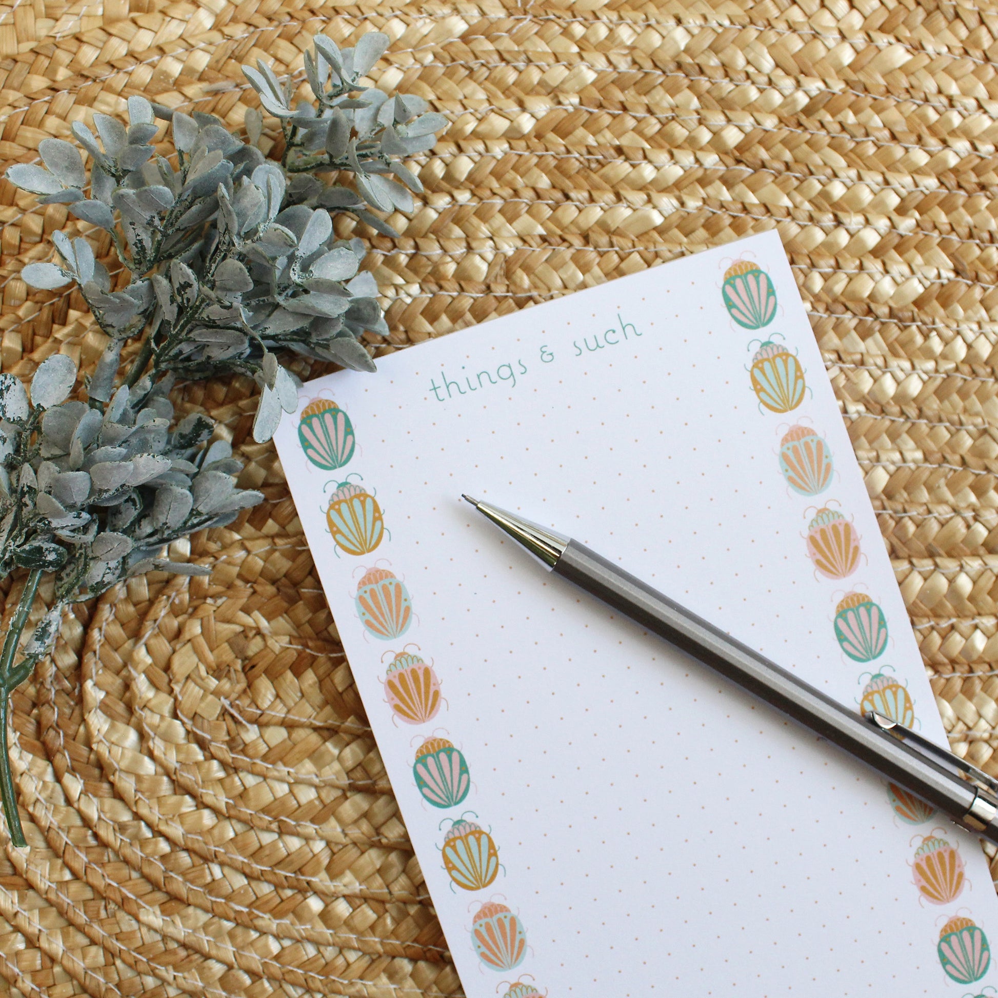 dotted notepad with colorful beetle illustrations going up either side of the paper.