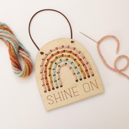 wooden rainbow banner stitching kit with shine on text and and yarn to stitch yourself.