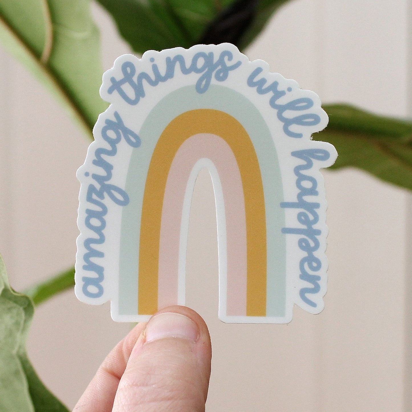 rainbow vinyl sticker in light blue, mustard, and pink with the words amazing things will happen in blue cursive text