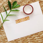 load image into gallery viewer, peach and yellow flower washi tape on a rust colored background.
